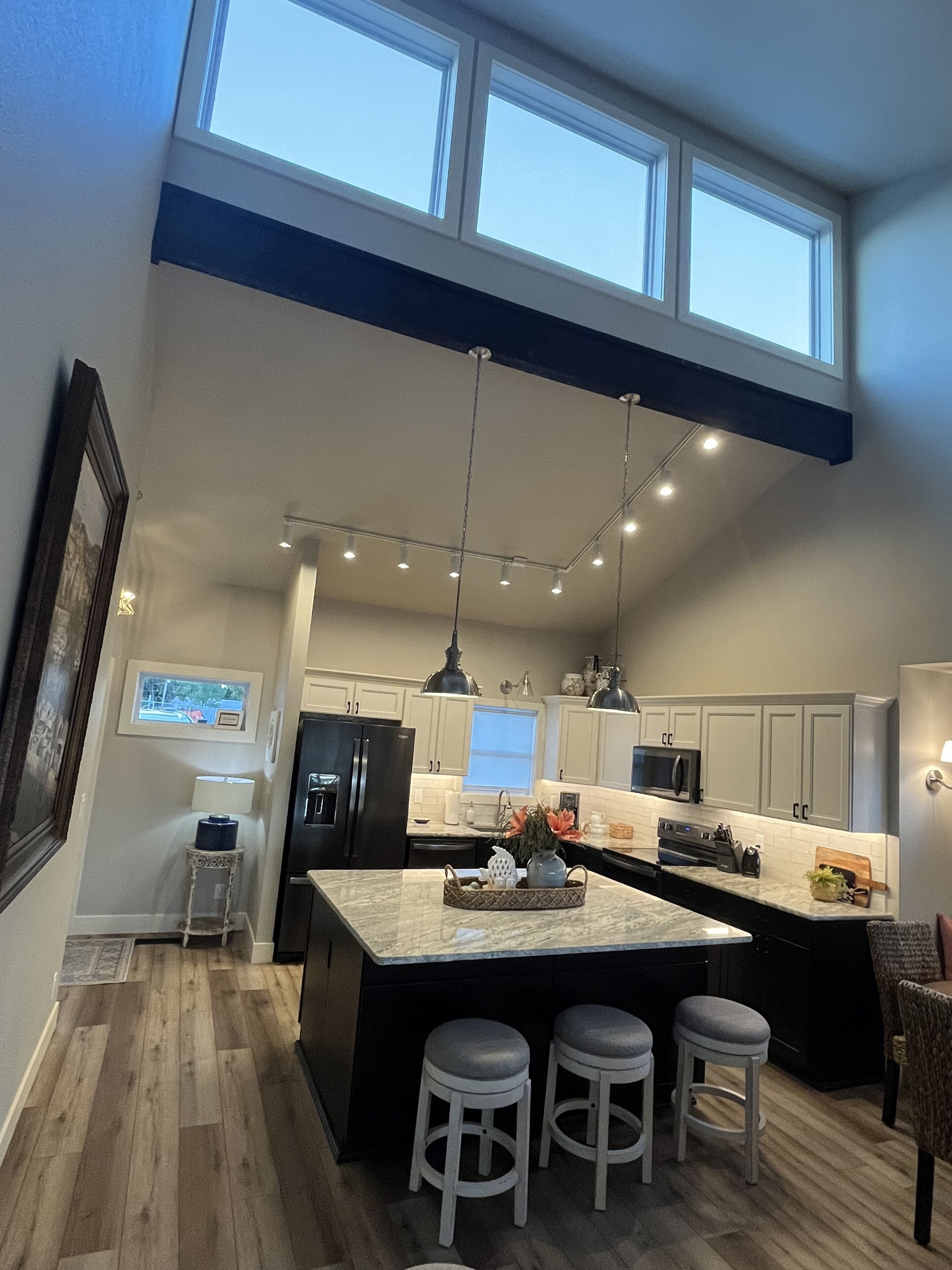 A modern kitchen with a large island, pendant lighting, and a view of the sky through the ceiling.