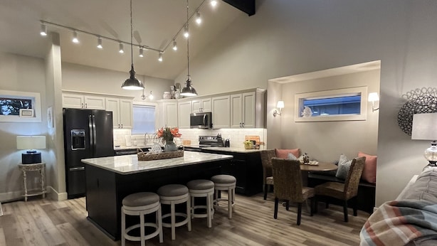 A modern kitchen with a central island, bar stools, and a dining area with a table and chairs.