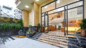 A hotel entrance with a marble staircase, a reception desk, and a view of the lobby. - PLUS VUNG TAU HOTEL (Ho Chi Minh City)