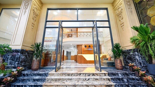 A hotel entrance with a grand staircase, a reception desk, and a balcony with decorative railings. - PLUS VUNG TAU HOTEL (Ho Chi Minh City)