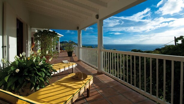 Une terrasse couverte avec vue sur la mer, comprenant un espace salon extérieur et des plantes en pot.