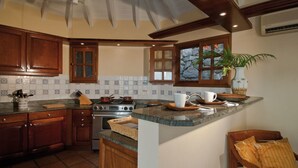 Une cuisine avec des meubles de rangement en bois, une cuisinière et une fenêtre donnant sur les arbres.