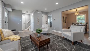 A living room with a grey sofa, a wooden coffee table, and a grey rug. - Koselig Retreat (Randallstown)
