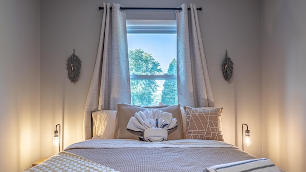 A neatly made bed with a patterned blanket, a folded towel, and decorative pillows. - Koselig Retreat (Randallstown)