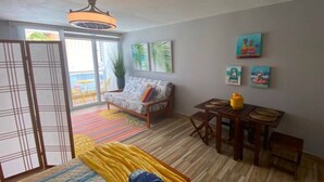 Una habitación con una cama, un sofá, una mesa de comedor y una mesita con sillas.