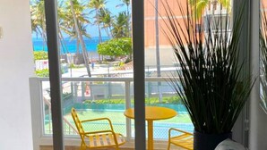 Un balcón con vista al océano, una piscina y una silla.