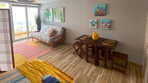 Una habitación con cama, sofá, mesa de comedor con sillas y un amplio ventanal con vistas.