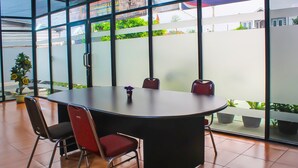A conference room with a large table, four chairs, and a potted plant.