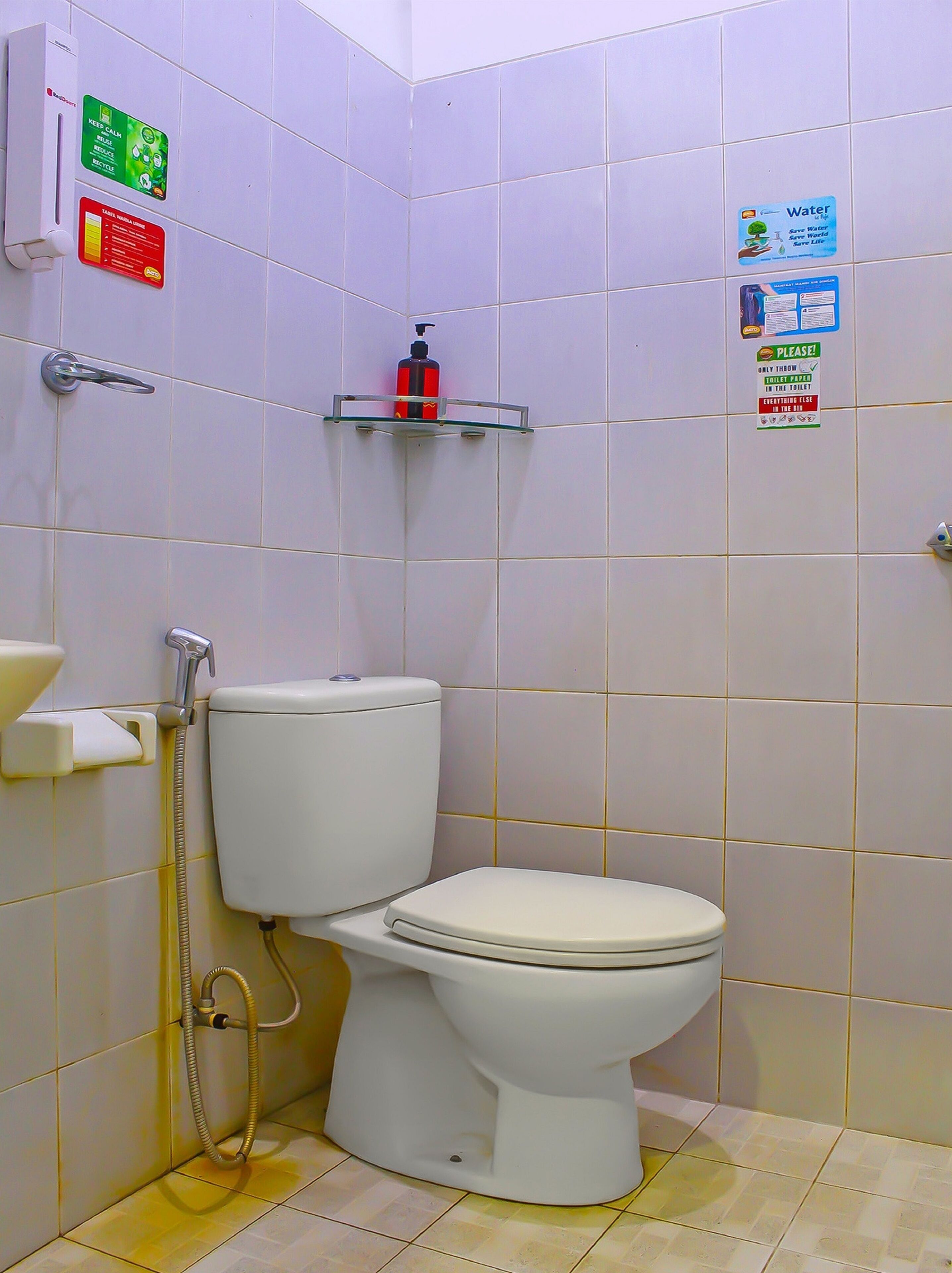Ein kleines, sauberes Badezimmer mit Toilette, einem Händetrockner und einem Seifenspender auf einem Regal.