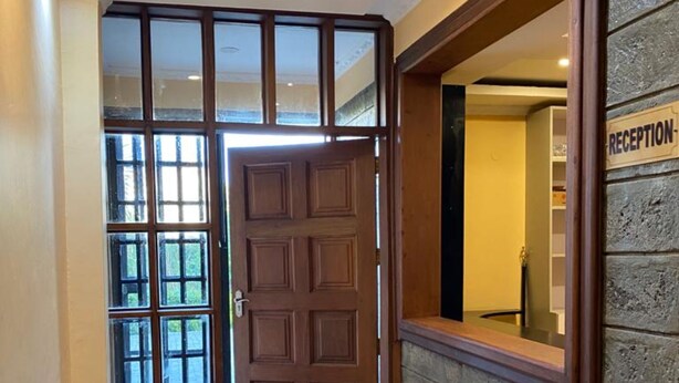 Un espace d’accueil avec une porte en bois, un banc et un mur en pierre.