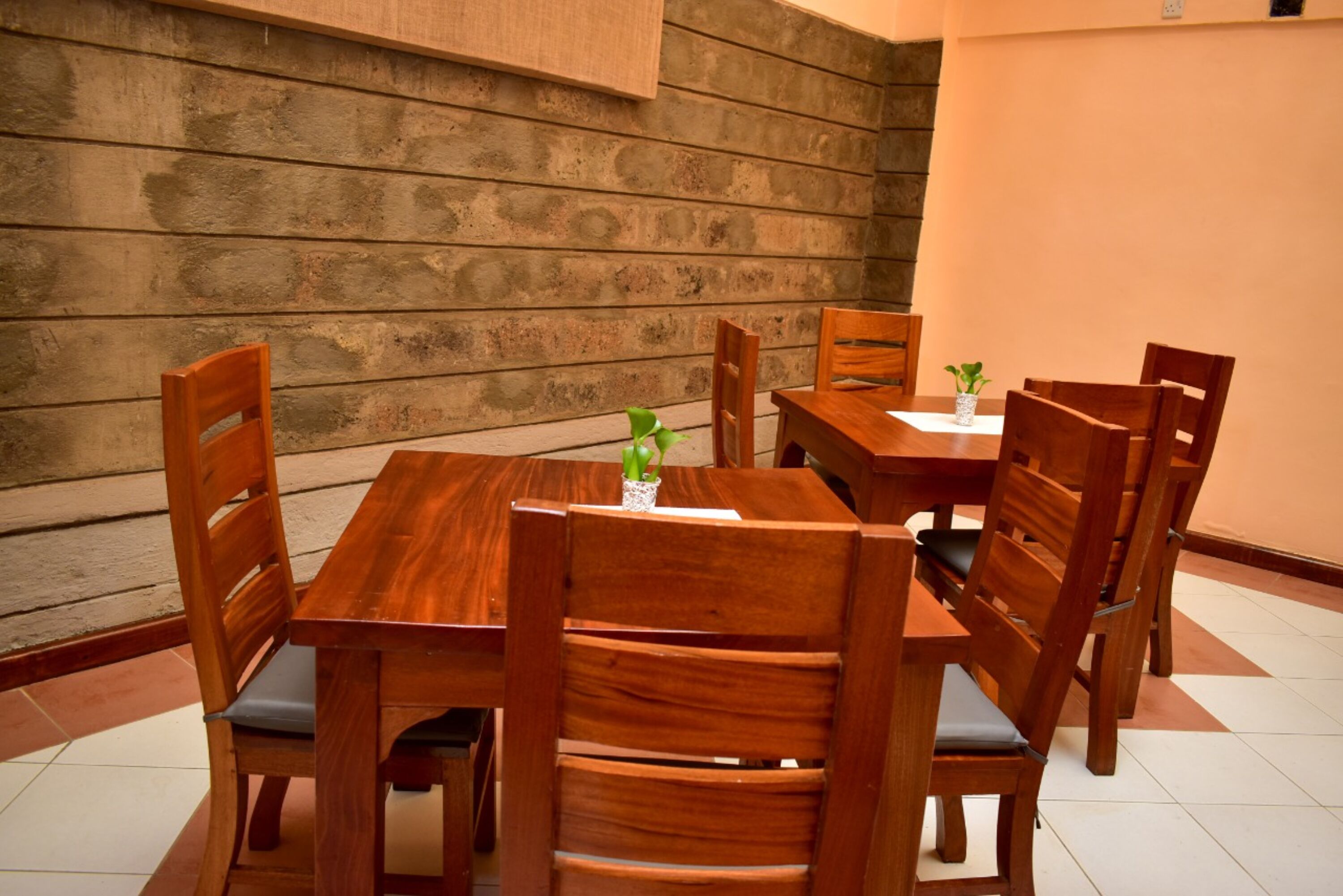 A wooden dining table with six chairs, a small potted plant, and a white tablecloth.