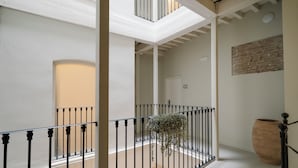 Ruime binnenruimte met een hoge plafond, een trap met zwarte leuningen en een grote potplant.