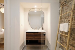 A bathroom with a wooden vanity, a large mirror, and a brick wall.