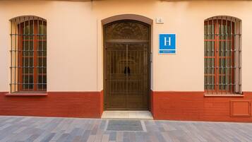 Entrada de un hotel con una puerta metálica, un letrero azul que indica el hotel y el número 4 en la pared.