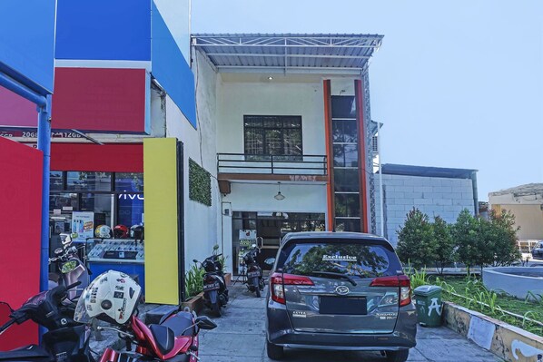 A building with a storefront, a parked car, and several motorcycles.