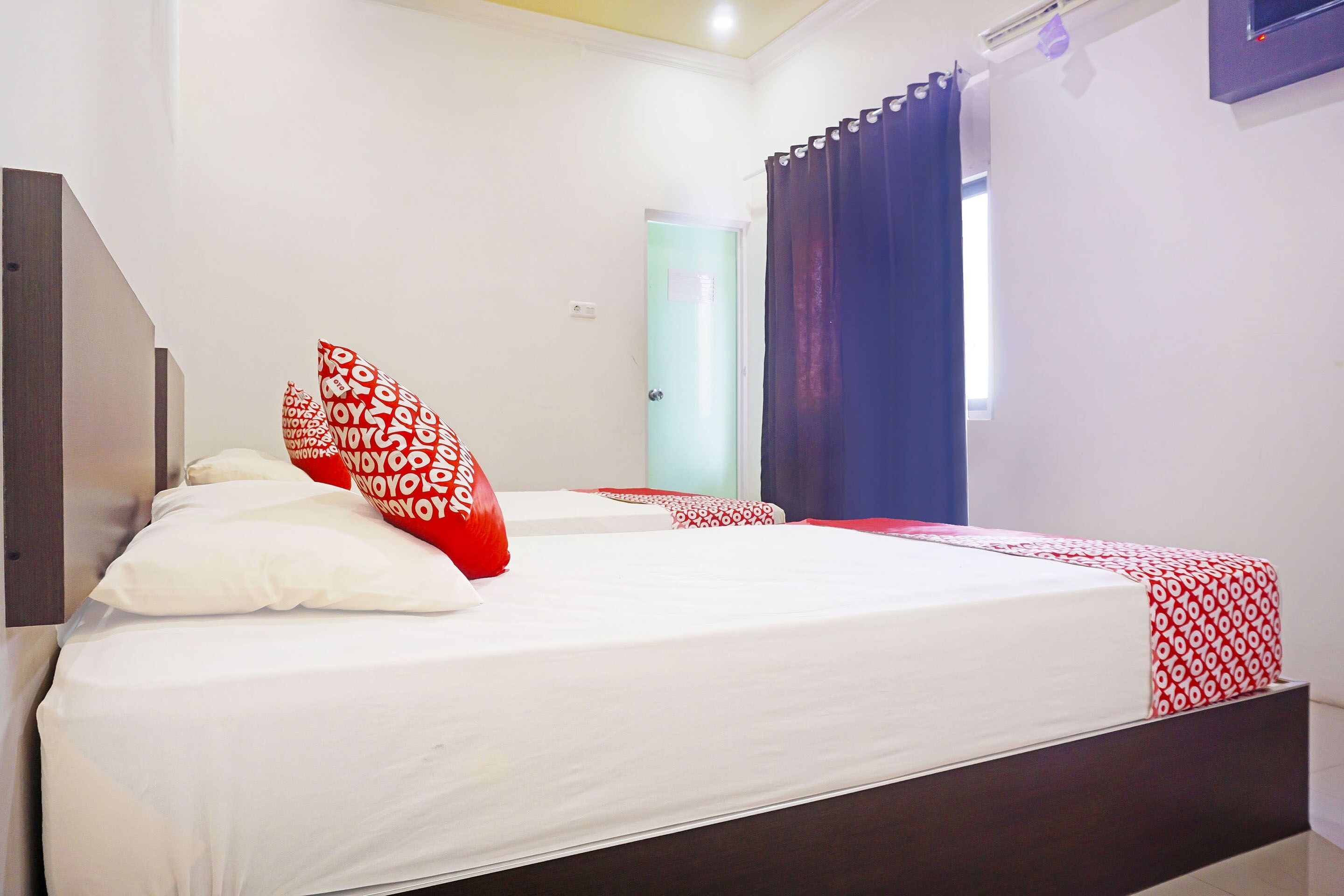 A hotel room with a bed, a nightstand, a window with curtains, and a door.