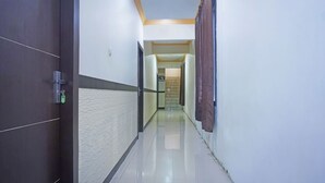 A hallway with a dark door on the left, a light-colored wall with a textured pattern, and a brown curtain on the right.