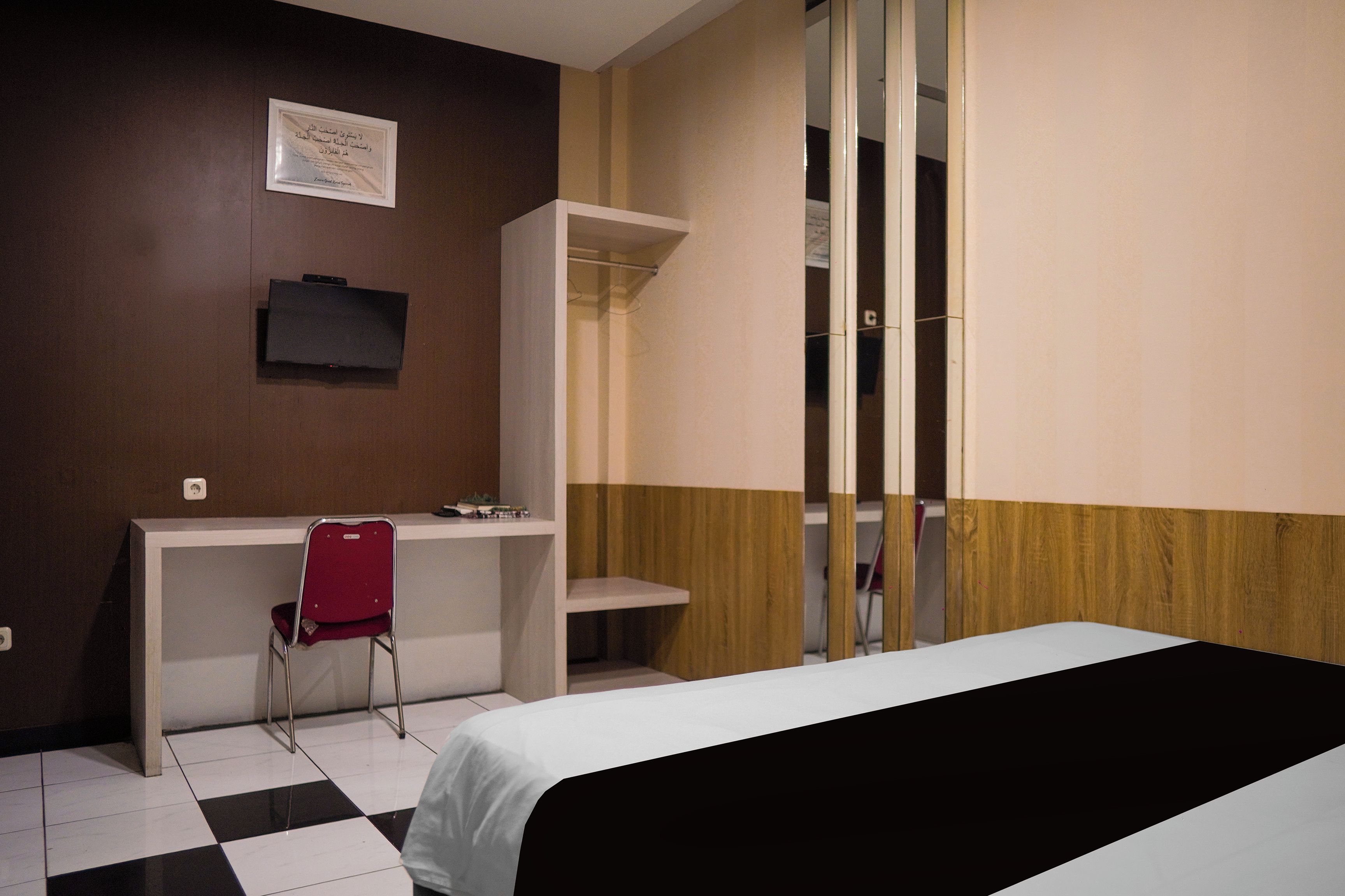 A hotel room with a bed, a desk, a chair, and a wardrobe.