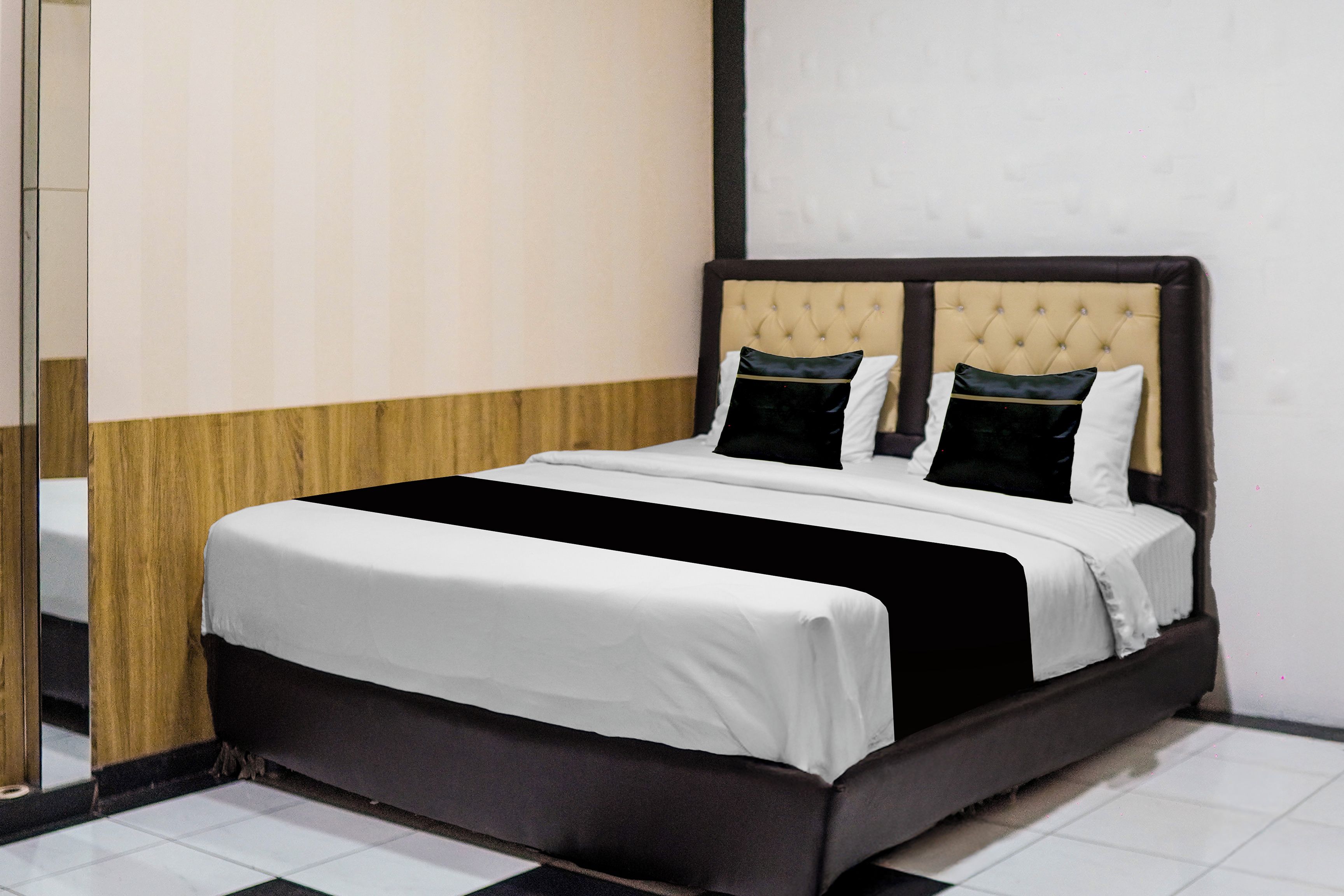 Une chambre d’hôtel avec un lit, un mur recouvert de panneaux en bois et un sol carrelé.