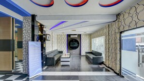 A modern lobby with a checkered floor, two sofas, a coffee table, and a circular wall feature. - Super OYO 4010 Zaara Guest House Syariah (Padang)