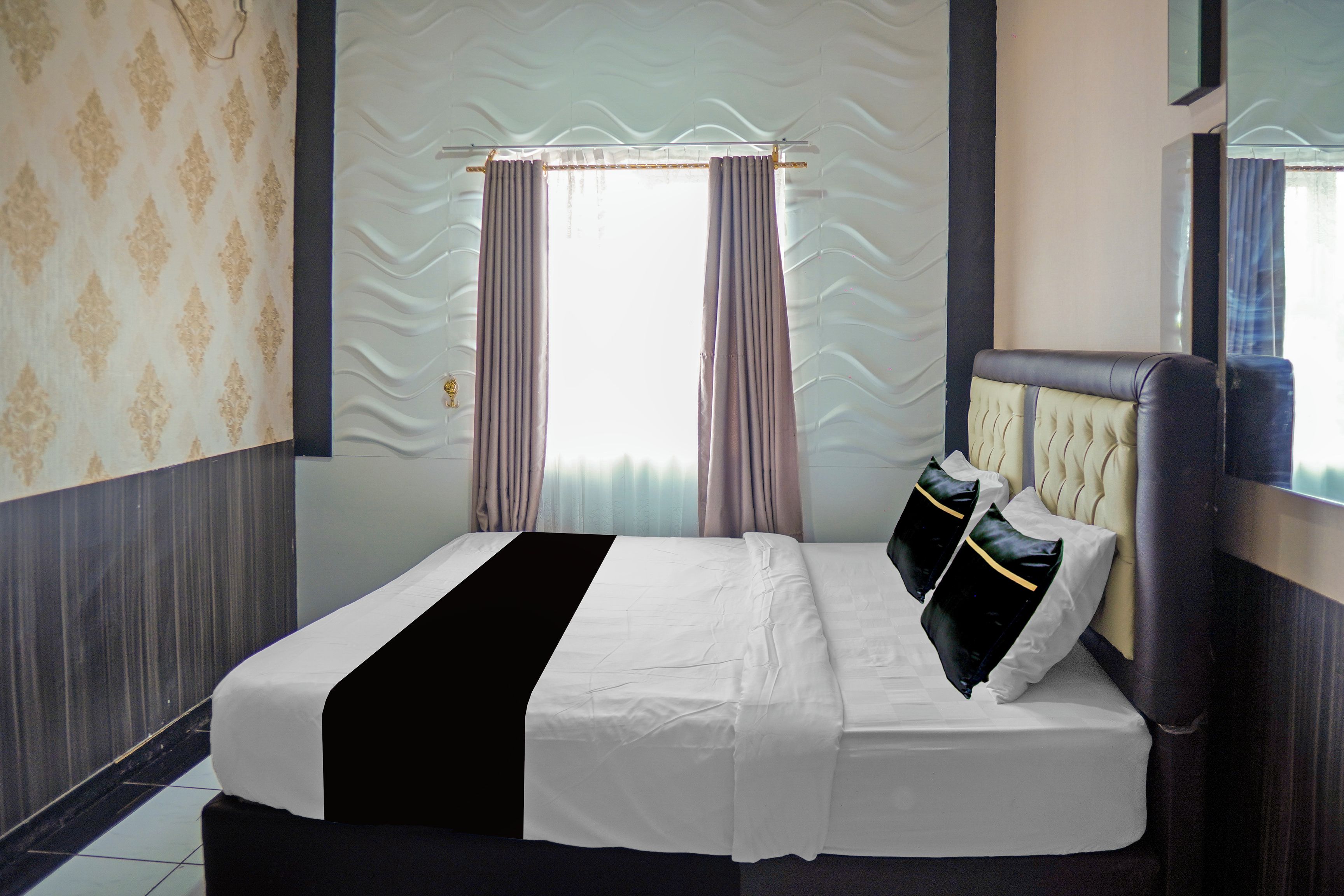 A hotel room with a bed, curtains, and a window.
