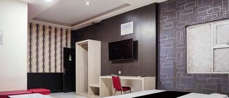 A hotel room with a bed, a desk, a television, and a wardrobe.