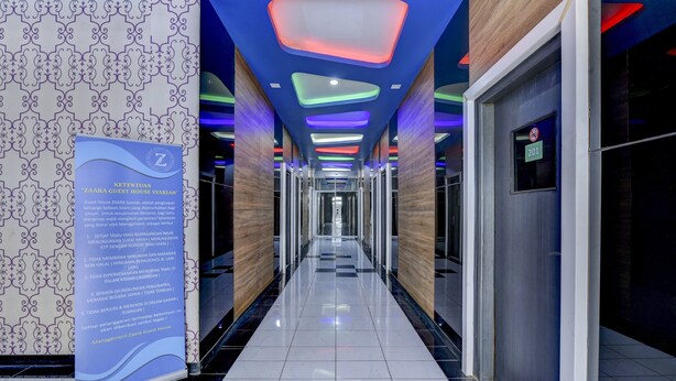 A hotel corridor with a patterned wall, a blue sign, and a ceiling with colorful lights. - Super OYO 4010 Zaara Guest House Syariah (Padang)