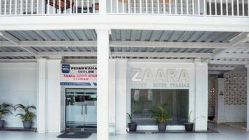 Un edificio con un letrero que dice 'ZAAARA GUEST HOUSE SYARIAH' y un anuncio de descuento que dice 'PESAN KAMA OFFLINE'.