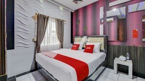 A hotel room with a bed, a nightstand, a mirror, and a window with curtains. - Super OYO 4010 Zaara Guest House Syariah (Padang)