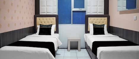 Quarto de hotel com duas camas, uma mesinha e uma janela.