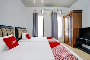 Une chambre d’hôtel avec deux lits, une armoire, un téléviseur et un appareil de climatisation.