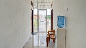 Ein Flur, der zu einer Glastür mit Blick auf ein Gebäude führt. In der Nähe der Tür befindet sich ein Wasserspender und ein Stuhl.