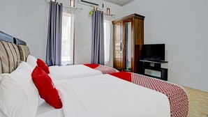 Ein Hotelzimmer mit zwei Betten, einem Fernseher und einem Kleiderschrank.