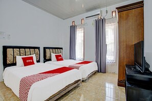 Une chambre d’hôtel avec deux lits, une télévision et une armoire en bois.
