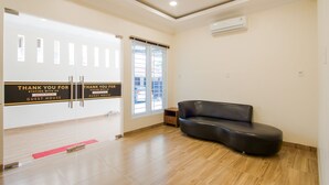 Un hall d’hôtel comprenant un comptoir d’accueil, un canapé en cuir noir et un mur de verre sur lequel est apposée une enseigne.