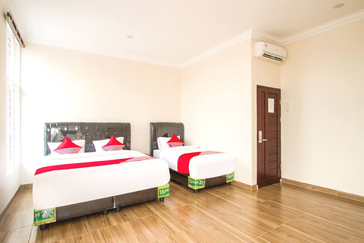 Une chambre d’hôtel avec deux lits, un plancher en bois et un climatiseur fixé au mur.