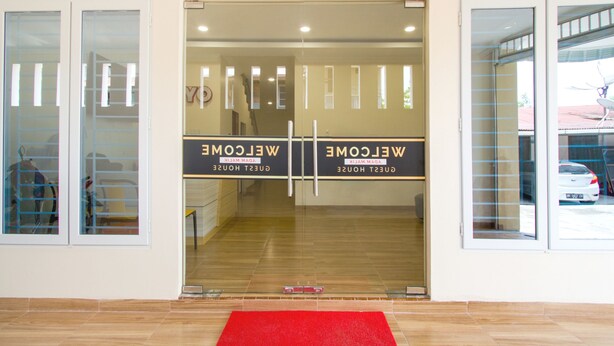 L’entrée d’un hôtel, avec un tapis rouge, des portes en verre et un panneau d’accueil.