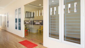 Un espace d’accueil d’hôtel avec une entrée dotée d’une porte en verre, un tapis rouge et un panneau d’accueil.