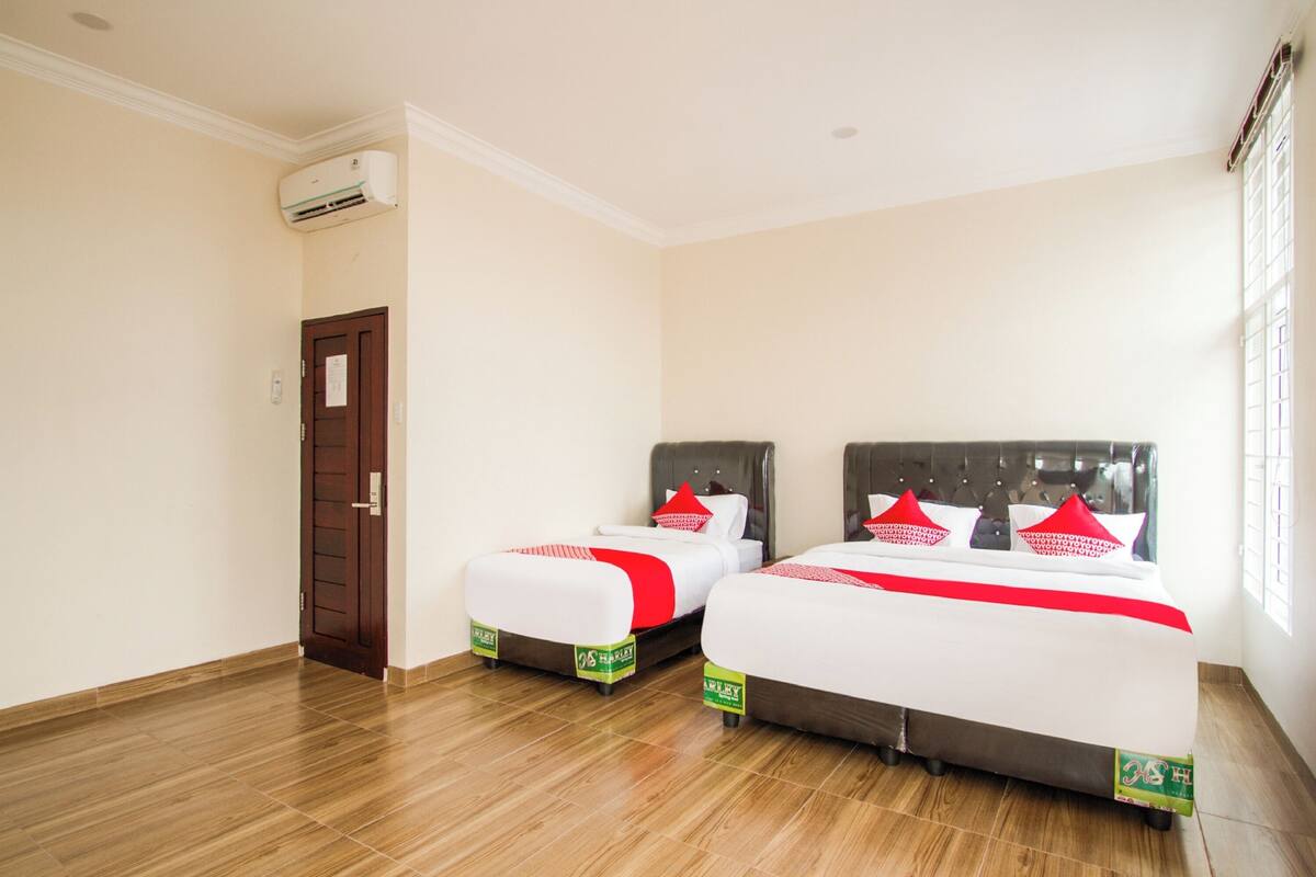 Une chambre d’hôtel avec deux lits, un plancher en bois, une porte et un appareil de climatisation.