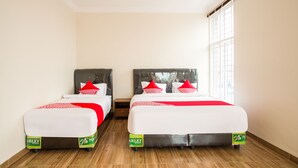 Une chambre d’hôtel avec deux lits, chacun doté d’un matelas blanc et de touches de couleur rouge, et une fenêtre donnant sur l’extérieur.