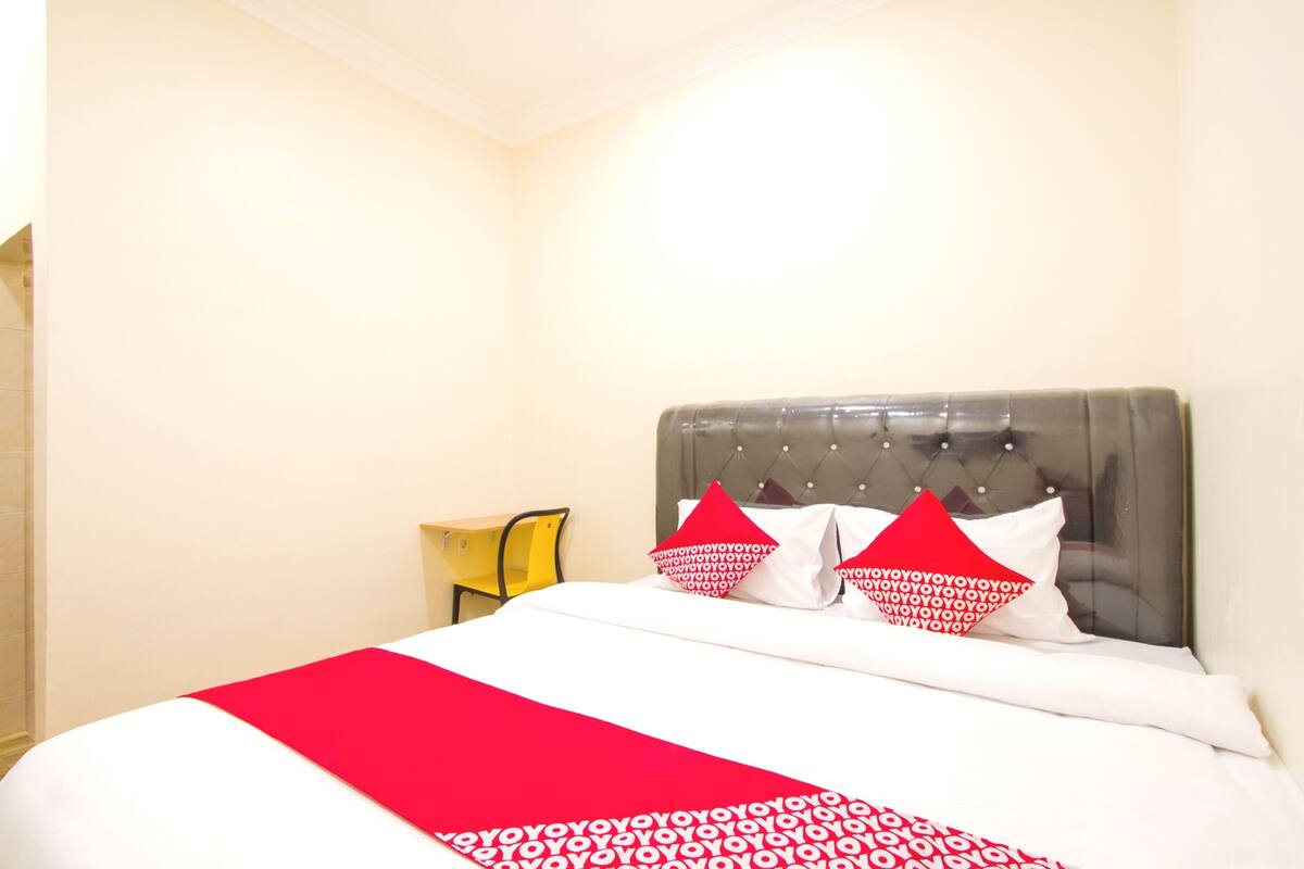 Une chambre d’hôtel avec un lit, une table de chevet et une couvre-lit à motifs rouges et blancs.
