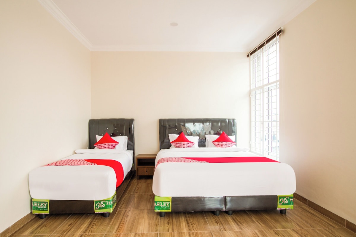 Une chambre d’hôtel avec deux lits, une fenêtre et un plancher en bois.
