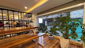 Um interior moderno com uma mesa de jantar de madeira, plantas em vasos e vista para o exterior.