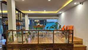 Decoração moderna com escada de madeira, área de estar com almofadas laranja e diversas plantas em vasos.