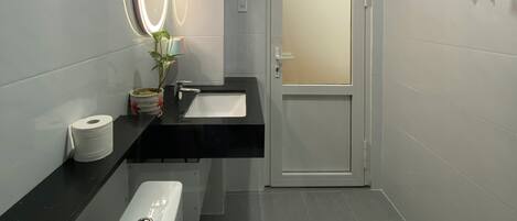 A modern bathroom with a toilet, sink, and mirror.