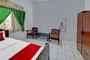 A hotel room with a bed, two chairs, a bench, a wardrobe, and a tripod against the wall. - SPOT ON 91372 Wisma Bulin (Banyumas)