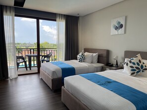Une chambre d’hôtel avec deux lits, un balcon avec des chaises et une vue sur l’extérieur.