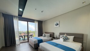 Habitación de hotel con dos camas, balcón y vistas al exterior.