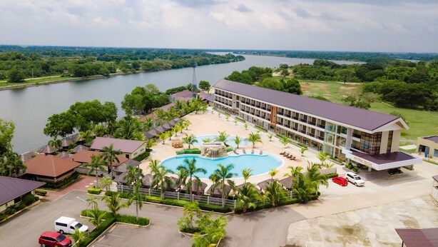 Un resort con piscina, palmeras y vistas a un río.