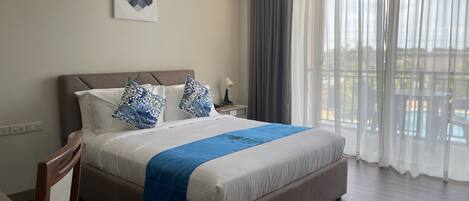 A neatly made bed with a blue throw, a headboard, and two decorative pillows.
